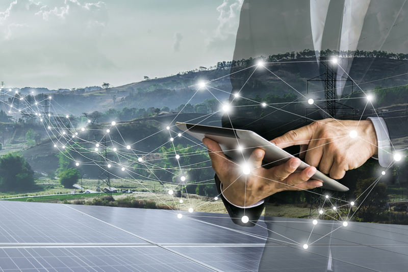 businessman holding tablet in front of solar panels